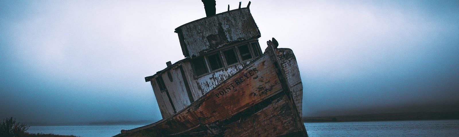 man on abandoned ship on shore