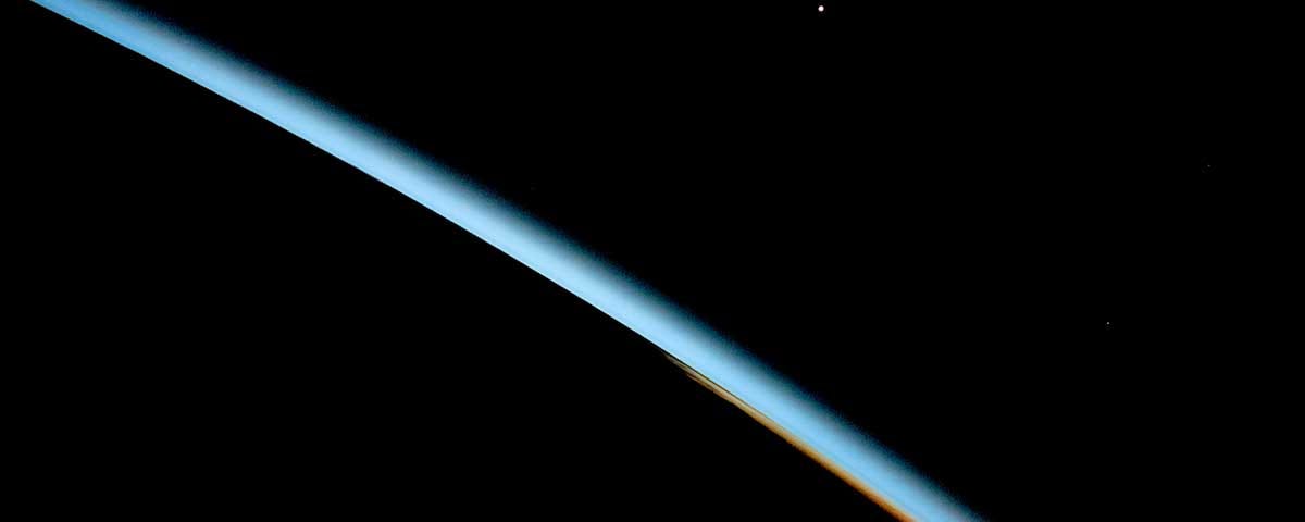 Earth’s limb as seen from the International Space Station at dawn over the Pacific Ocean in May 2019. The thin layer of gases that make up the atmosphere is visible because the gas molecules scatter, absorb, and refract sunlight.