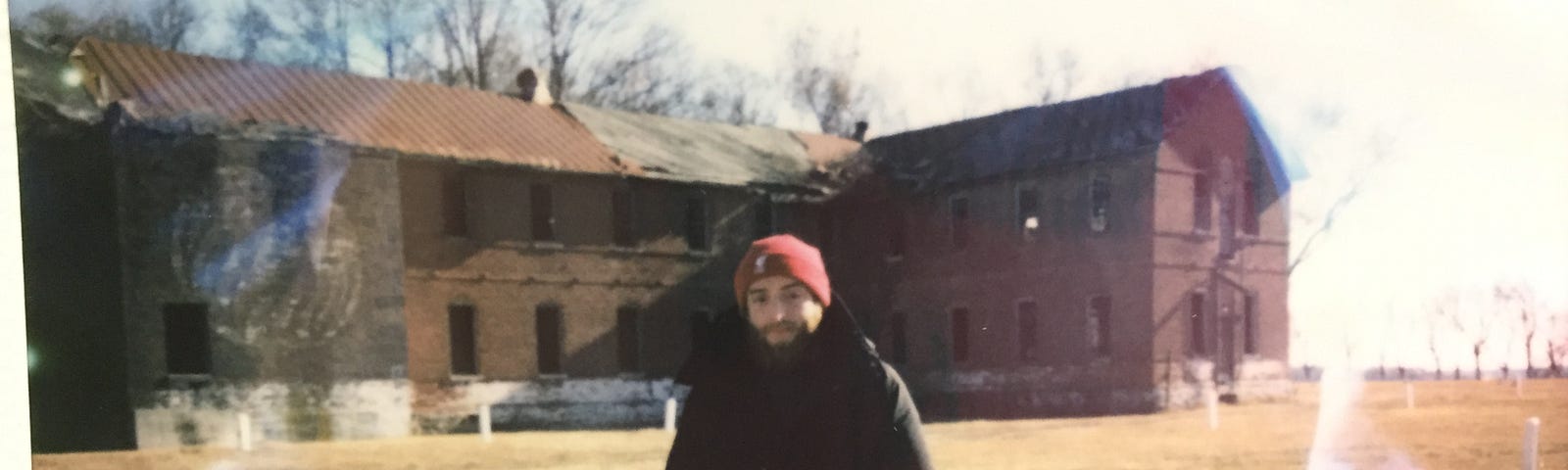 A photograph taken of the author, Michael Agovino, by a wonderful corrections officer. Behind the pillars was the Pheonix Rehab facility, which functioned in the 1970’s. It is crumbling apart and the corrections officer stated that he still finds shoes, clothing, and books in the ruins of the building.