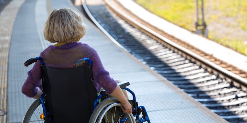 Lady in a wheelchair waits for a train at a rail station. Stock image from Shutterstock.