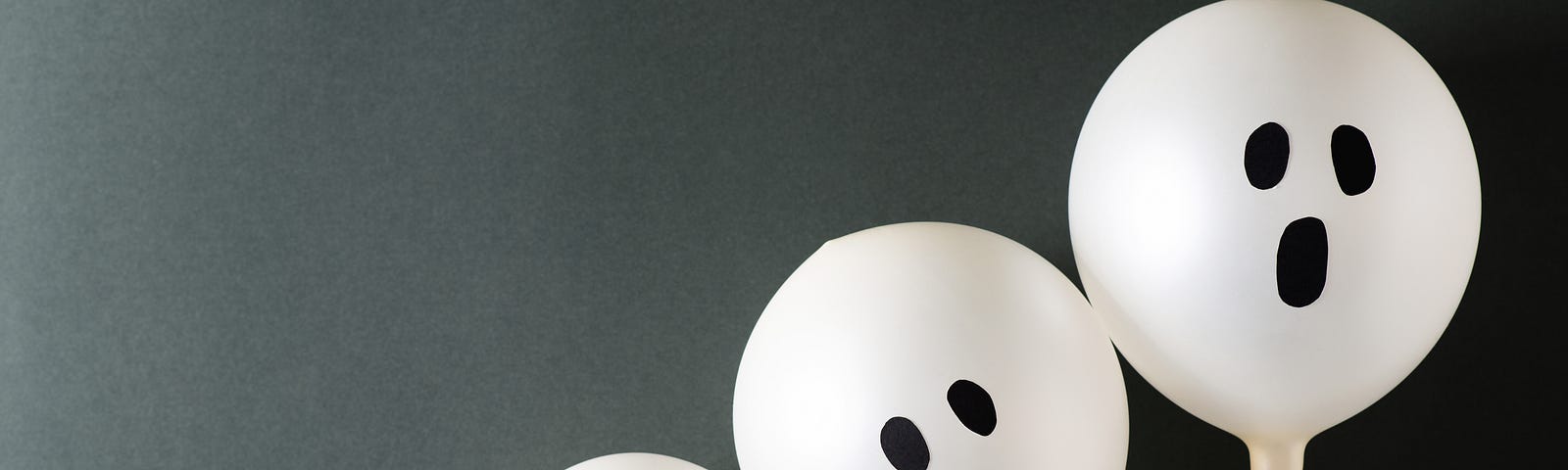 Three small ghost balloons sit clustered together from smallest to largest.