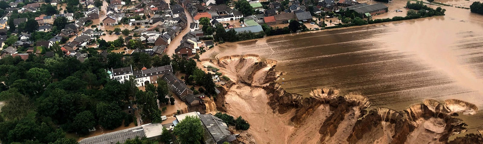 An aerial image of a German town where a quarry dam collapsed from the extreme flooding and a massive sinkhole has swallowed buildings and cars.