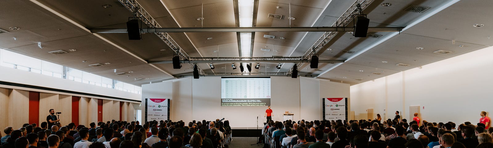 Photo of a large conference room full of people looking at the screen