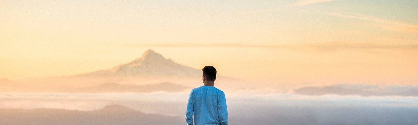 A person standing on a mountain at sunset.