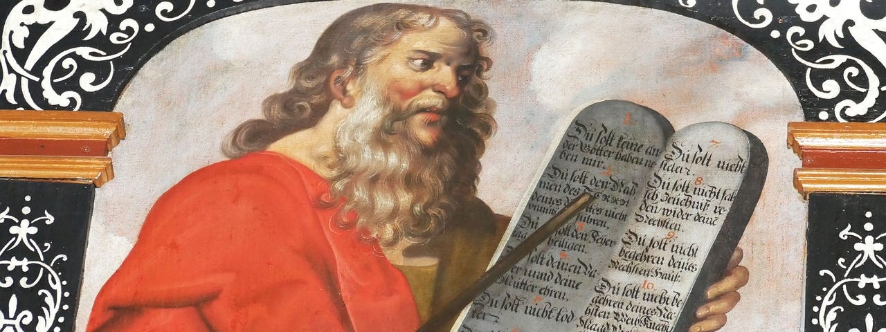 Old fashioned painting of red-robed, flowing whiskered Moses holding a tablet of the ten commandments.