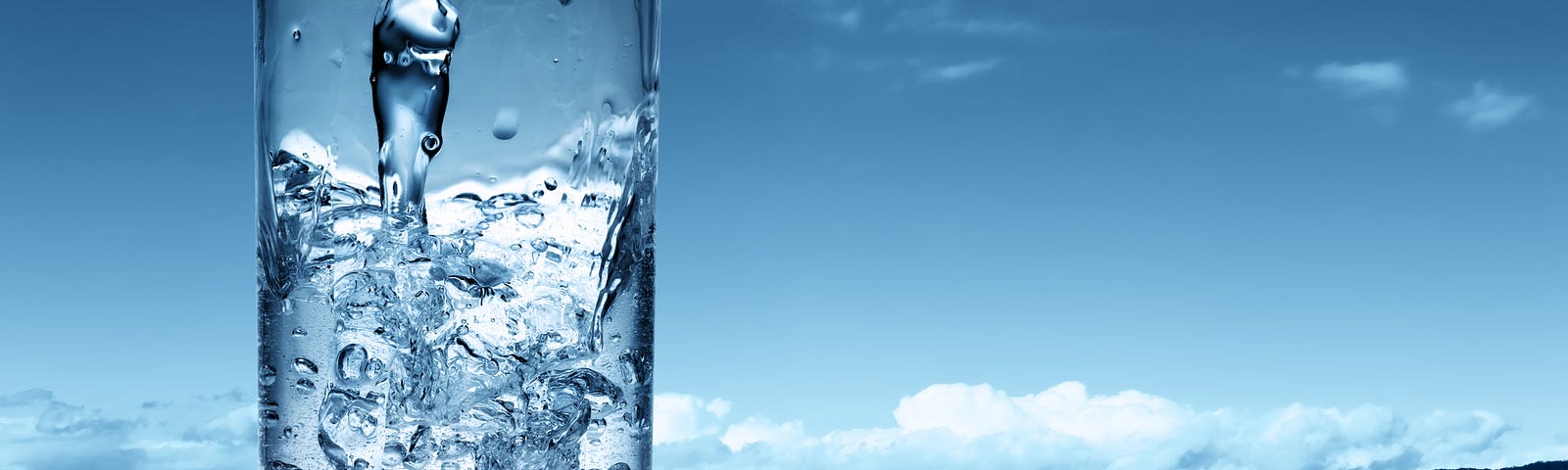 A glass of water being filled on a blue background with the sky and ocean (water fasting, intermittent fasting, I water fasted 28 days, what happens when you water fast 28 days, water fasting results)