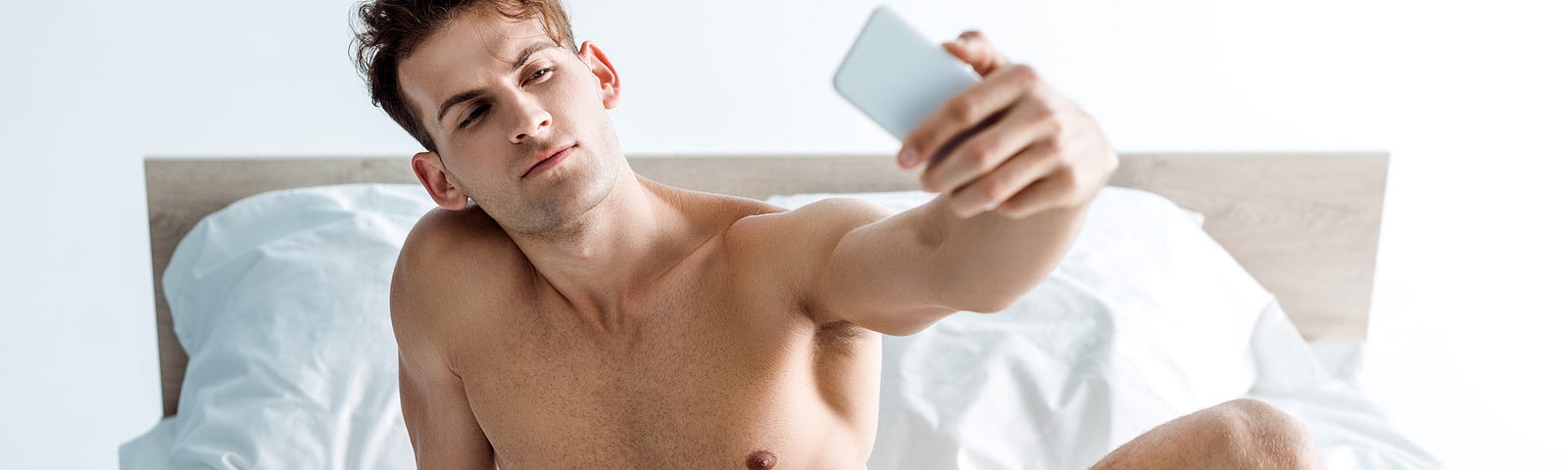 A shirtless man in his underwear taking a photo to sext with someone