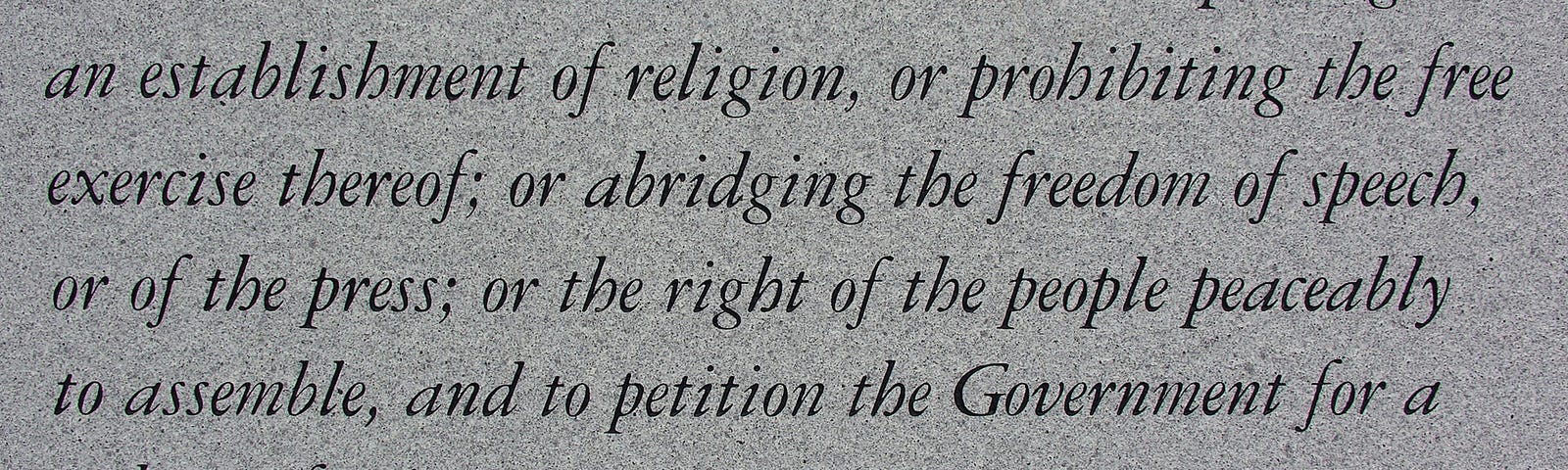 A photograph of a stone plaque engraved with the First Amendment to the United States Constitution