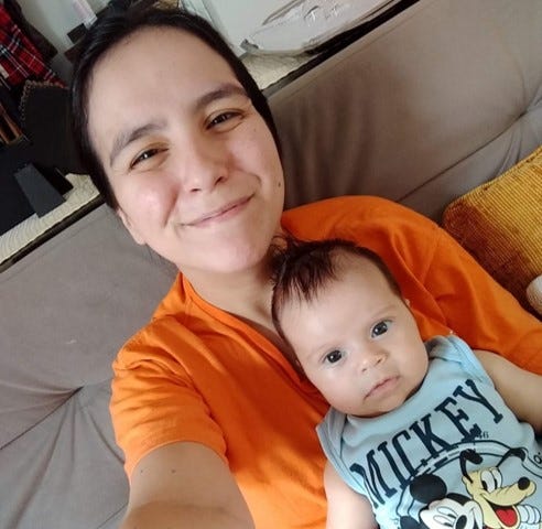 Uma mulher com seu filho, ainda bebê, no colo.