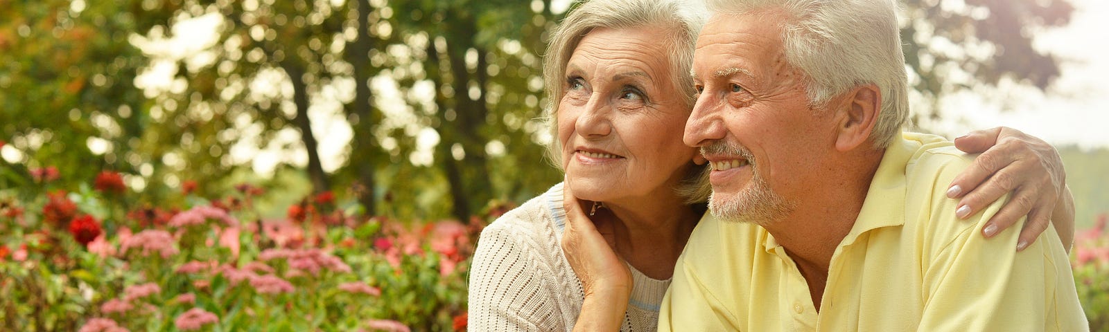 Older man and woman smiling surrounded by flowers (living apart together relationships, LAT relationships, older couples, aging, senior citizens)