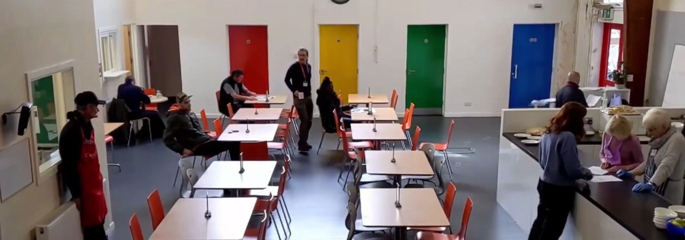 The Cornerstone Centre, featuring rows of tables and colourful doors and a food counter.