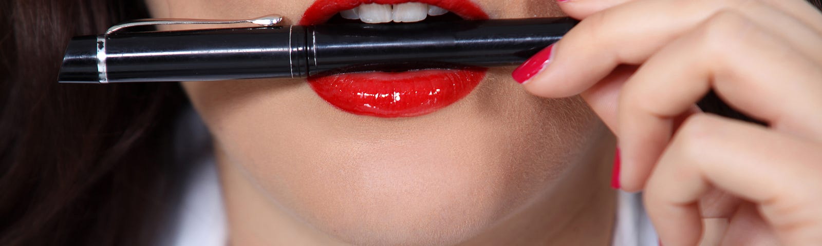 Woman with red lipstick holding a pen in her mouth.