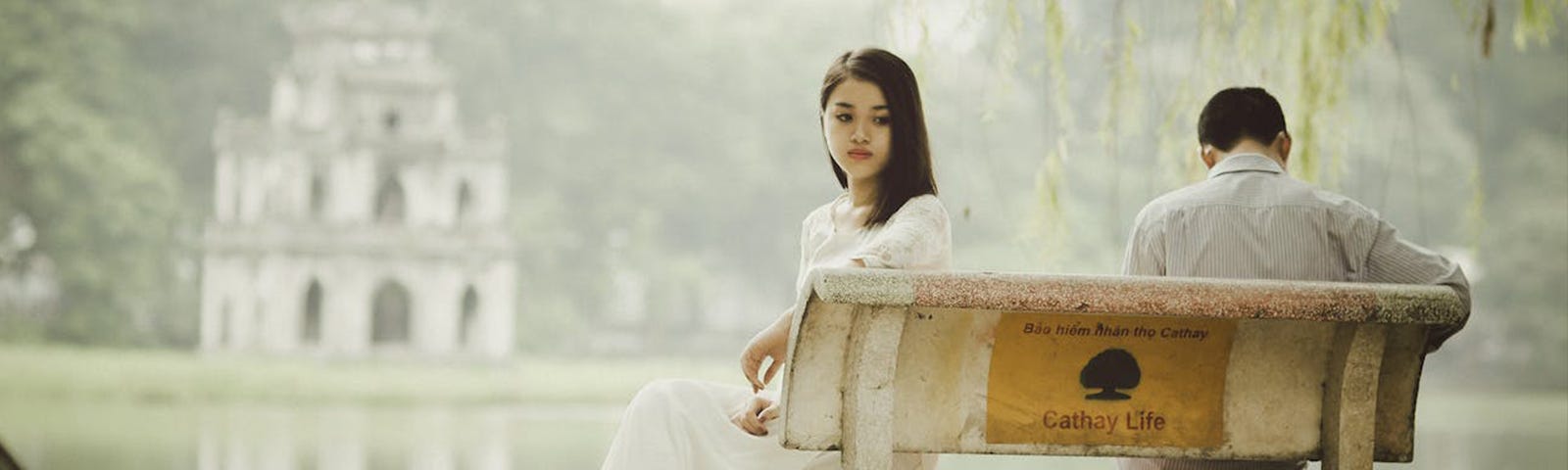 woman and man sitting on a bench upset