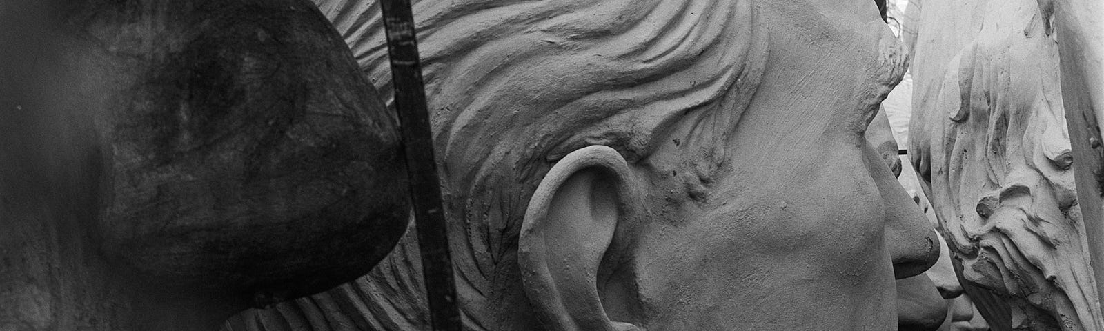 Close up of colossal sculpted heads, in profile, especially the noses