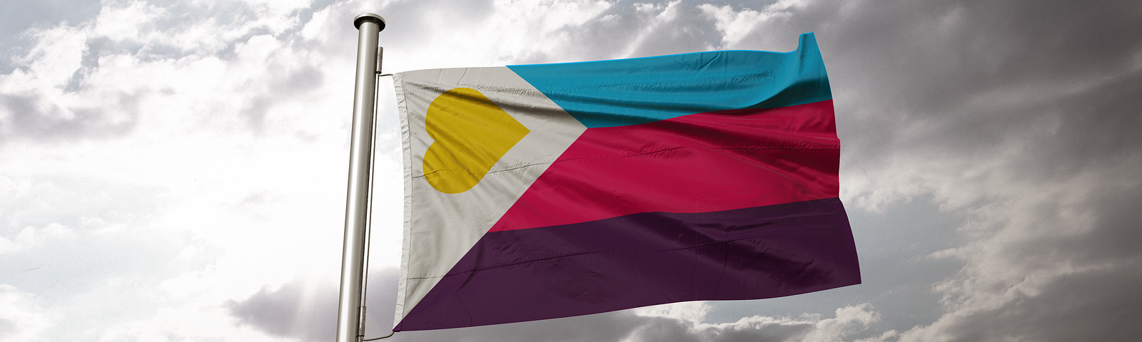 The Polyamory Pride Flag flying at mast against sky with the sunlight shining through the clouds. A tricolour flag with red, blue, and purple stripes, with a white chevron with a gold heart.