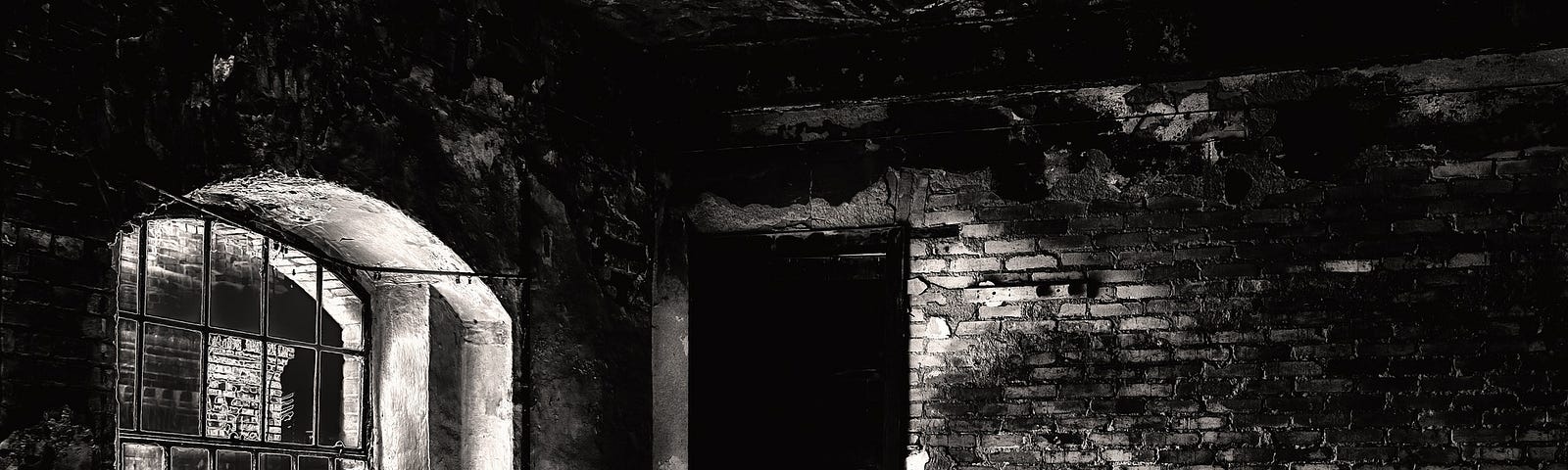 Dark basement with brick walls, dirt floor, and dirty broken window