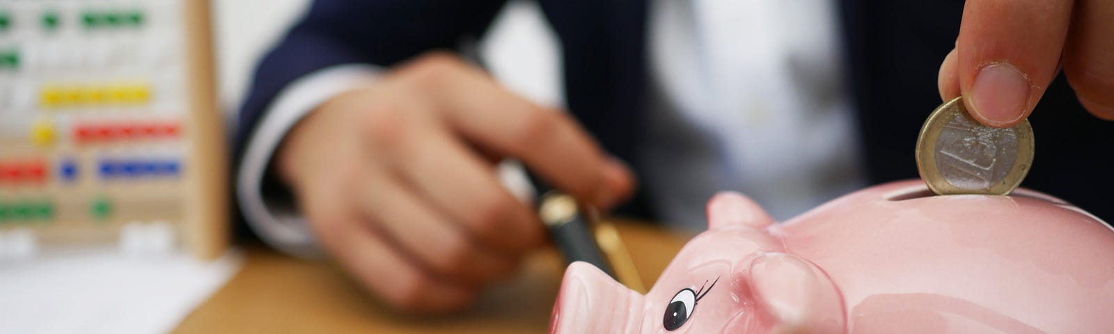 Person inserting coin into piggy bank