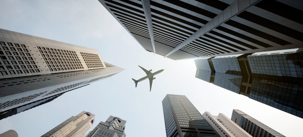 Airplane flying over city buildings.