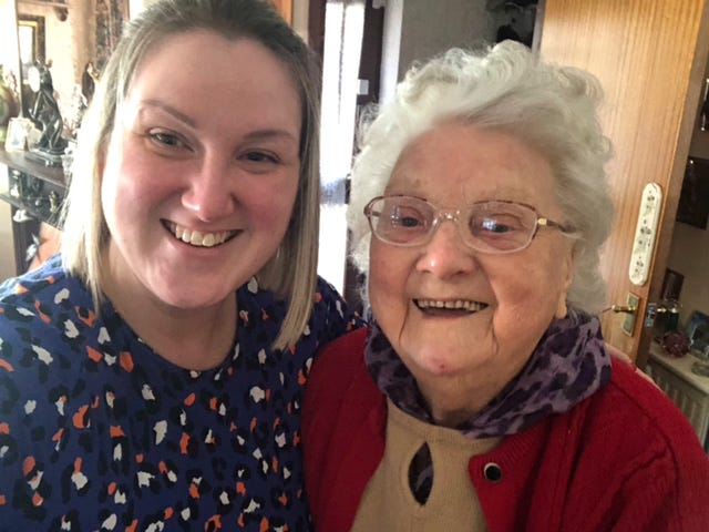 A young woman and an older woman smile at the camera together.