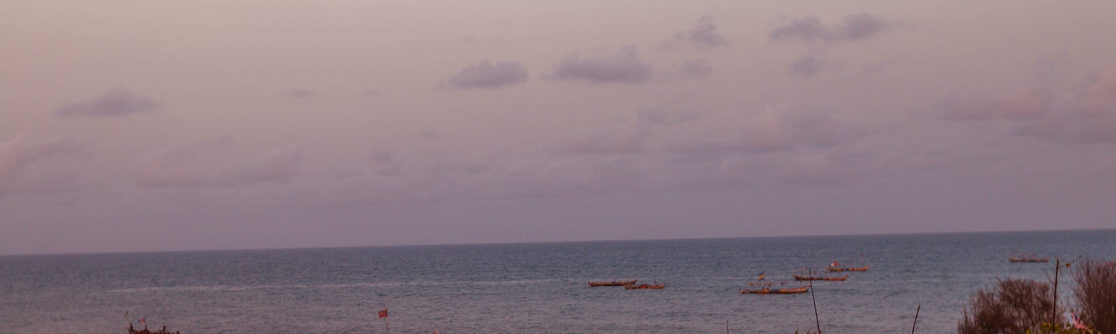 A shot of some canoes on the sea, in a distance