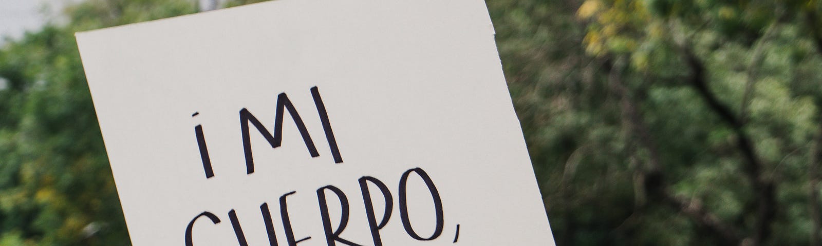 Photo of a person holding a sing that reads “My body, my choice” in Spanish.