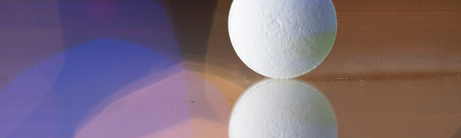 Close-up of a reflected pill on a reflective surface. Colorful lights background.