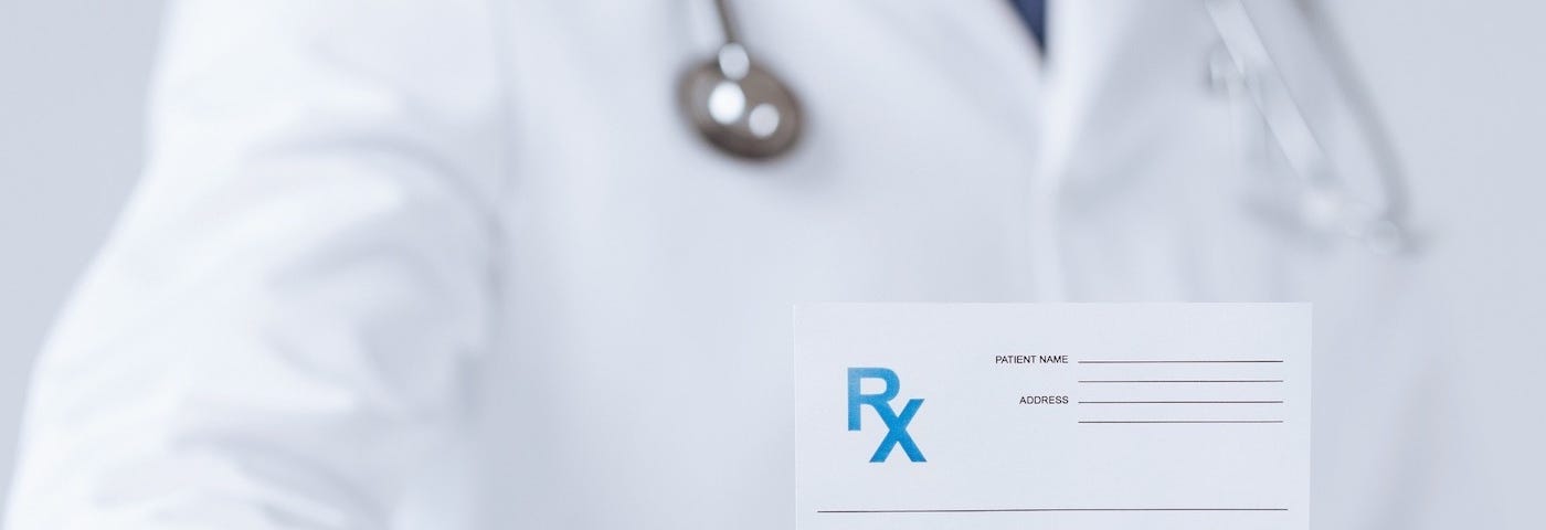 Person in white coat holding prescription