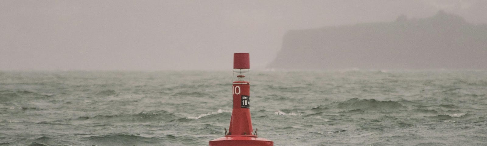 Red buoy in the ocean and foggy skies.