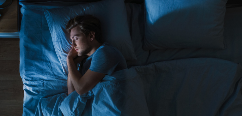 Top View of Young Man Sleeping in a Bed at Night