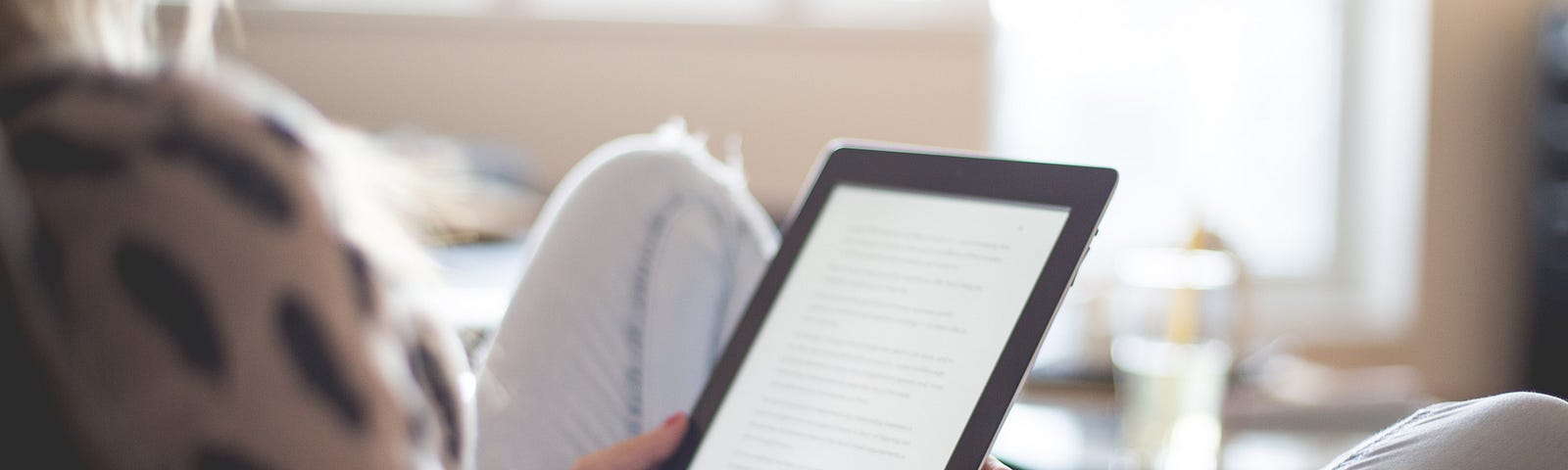 Woman sat in an armchair at home holding a tablet