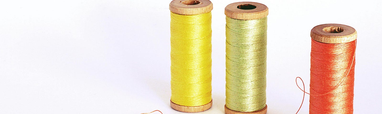 A trio of spools of thread, one yellow, one green and one red