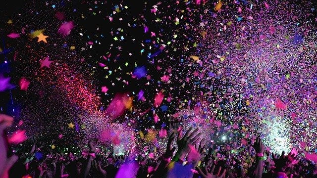 Multi colored confetti thrown in the air on a black background