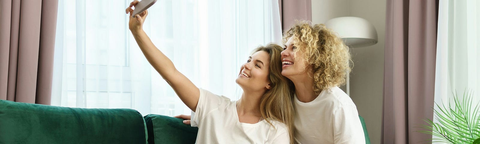 Two women taking a selfie with a smartphone. Little do they know, they’re working for Big Tech for free.