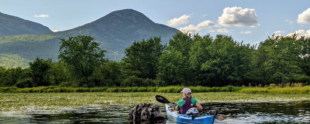 A kayaker paddles in the direction of a mountain.