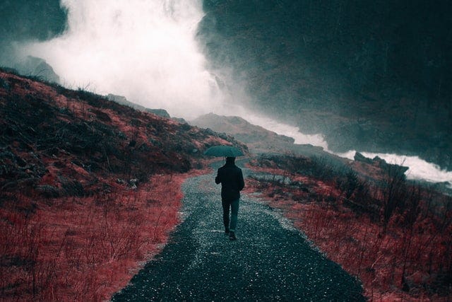 a person walking in a storm down a paved road.