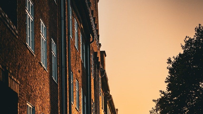 Sun shining on the side of a building as it sets.