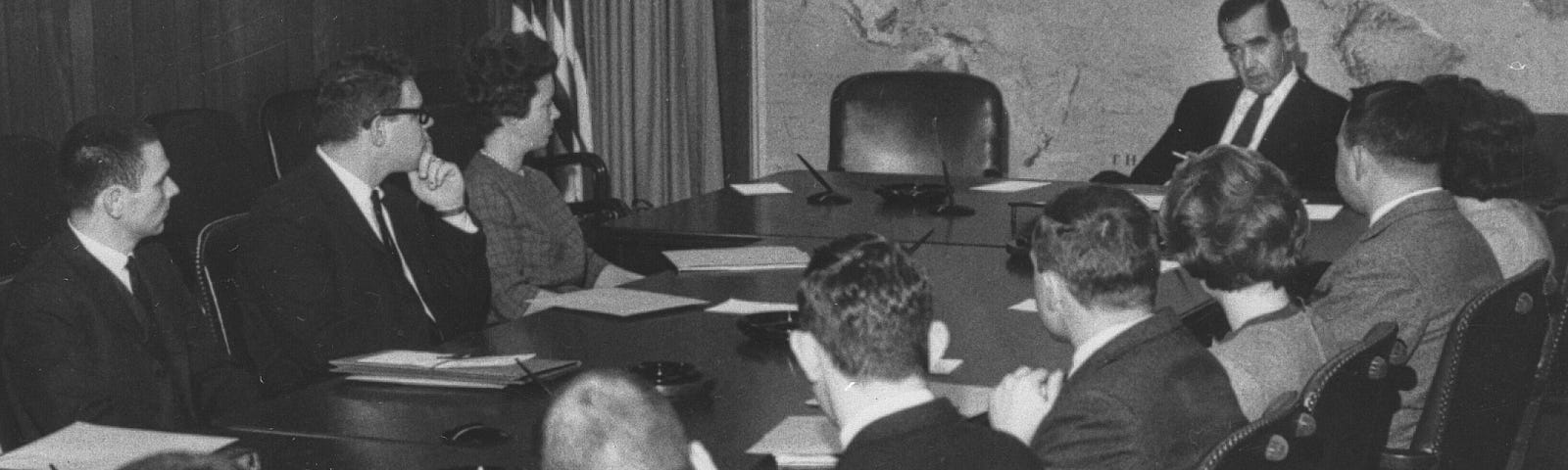 Black and white image of Edward R Murrow meeting with new foreign service officers around a conference table