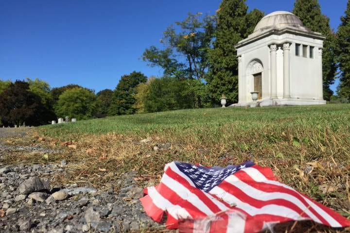 Crumpled American flag on grass in front of Oakwood Cemetery.