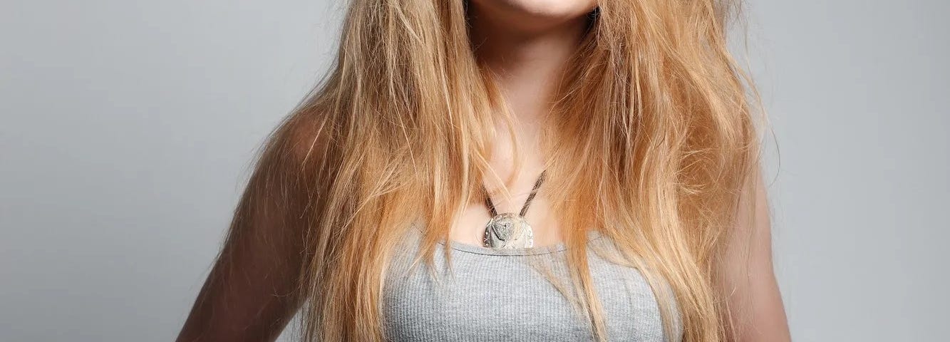 Young woman with long blonde hair about to lift her t-shirt