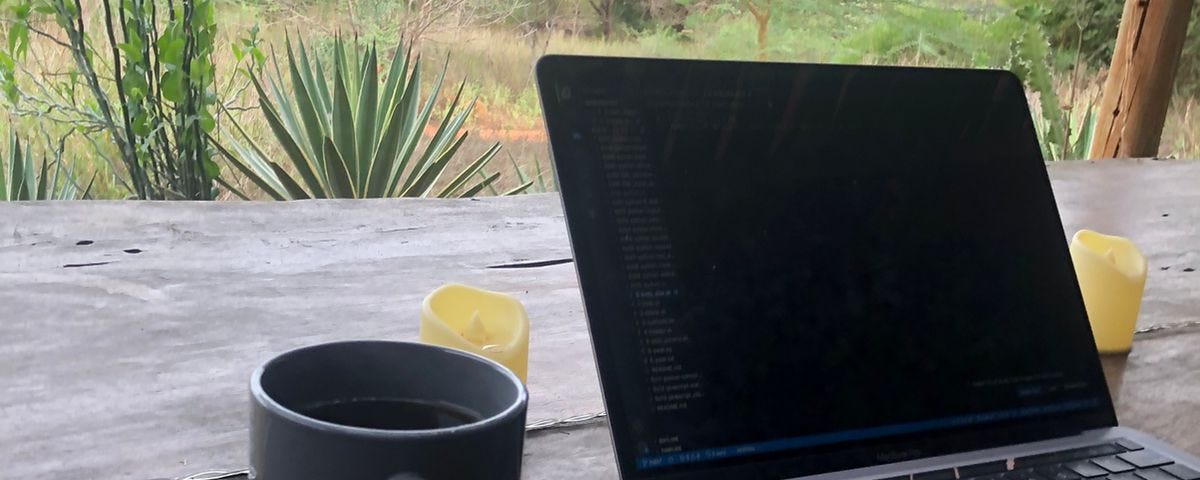 A MacBook pro with a cup of coffee sits on a wooden desk