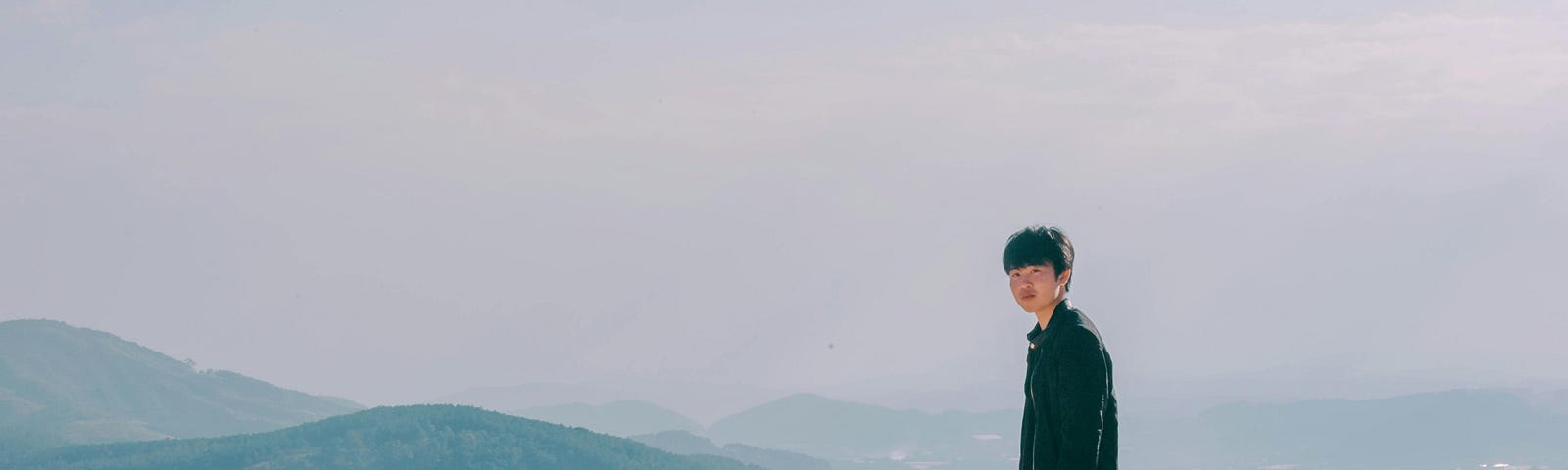 Young man standing against a backdrop of mountains