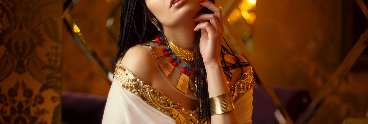 Egyptian styled female model, Cleopatra, sensual white dress, gold accessories, braided hair and strappy sandals