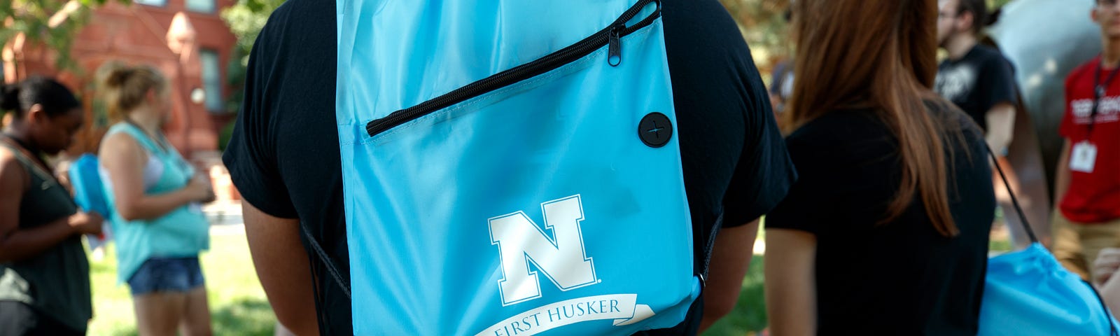 At an event for first-generation college students, they stand in a circle for discussion with “First Husker” backpacks on