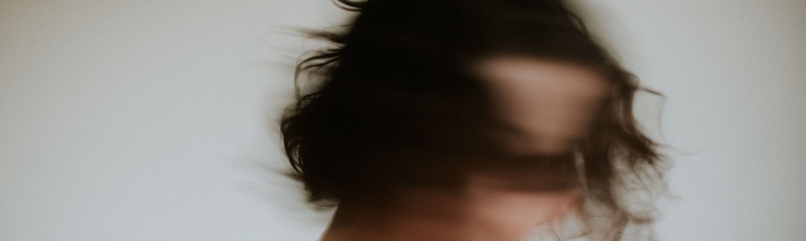 Blurred woman with dark hair shakes her head from side to side.