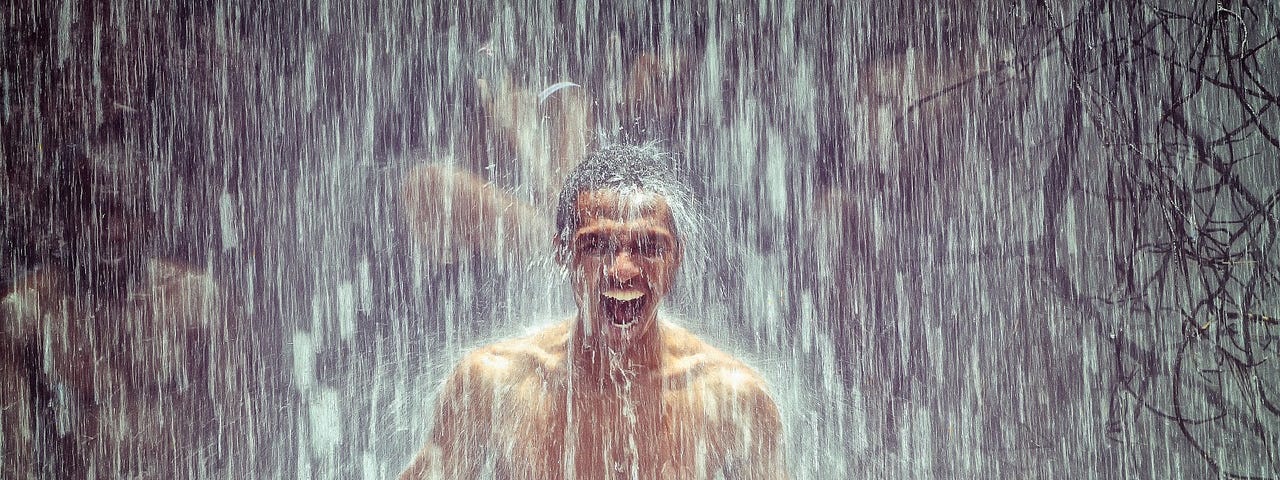 Man laughing under a heavy showerof rain.