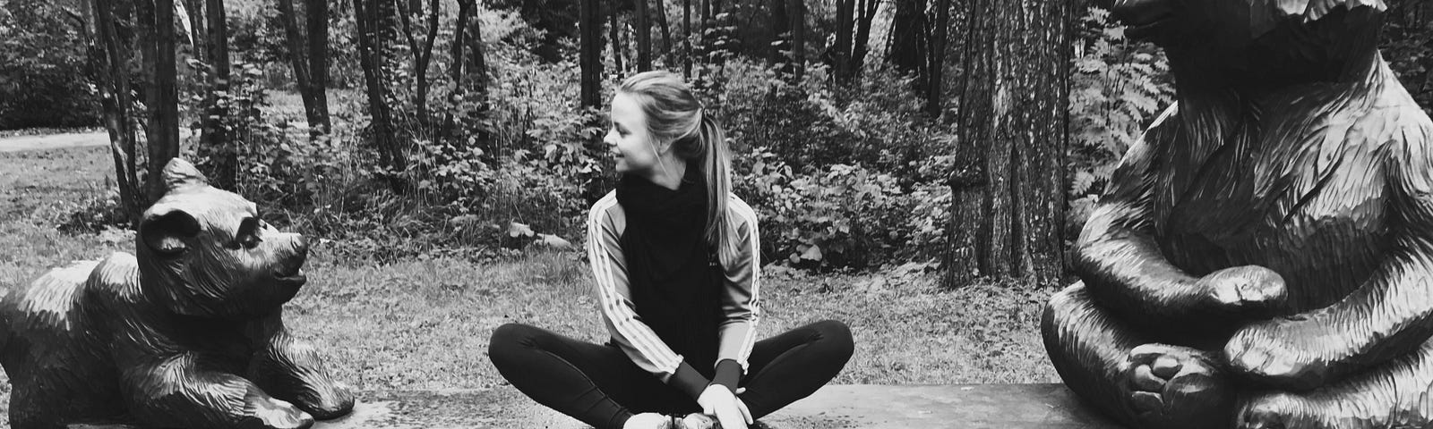 author sitting cross-legged on the bench in the forest