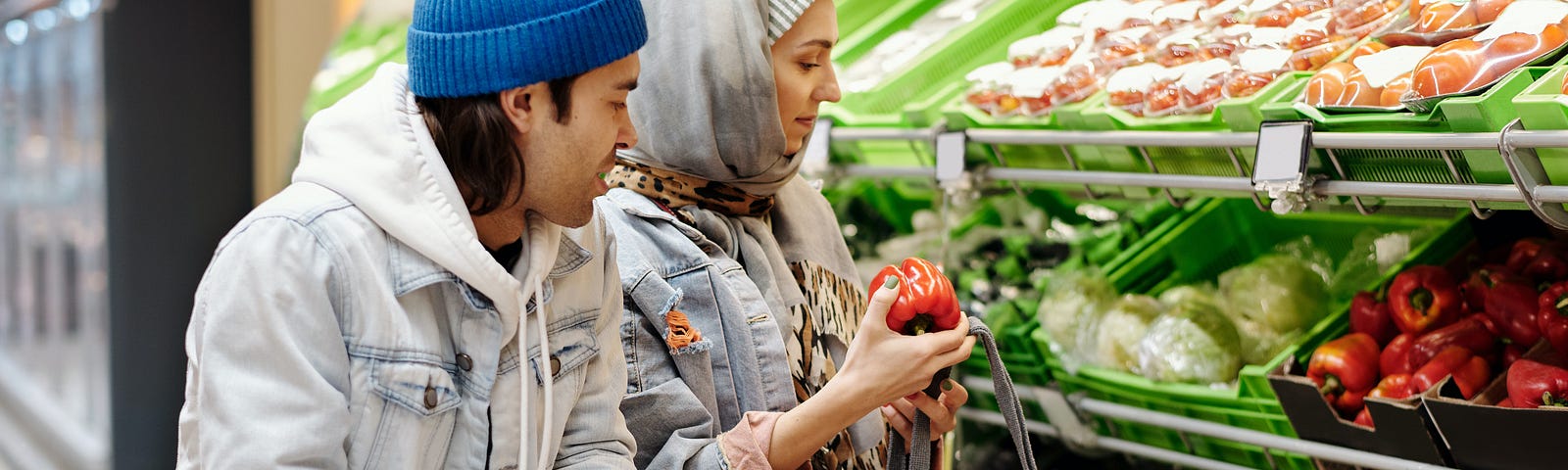 Man and a woman shopping in a grocery store looking at fresh vegetables