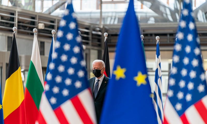 President Joe Biden walking through a ring of world flags.