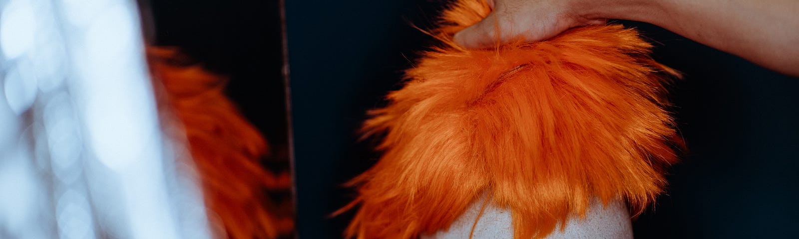 A hand grabs an orange wig from a dummy head.