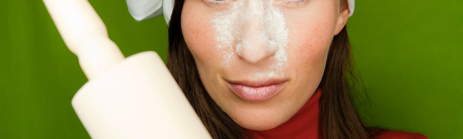 Woman with flour on face holding a rolling pin.